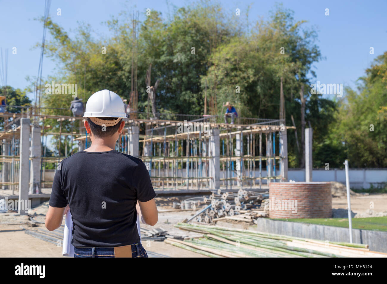 Porter un casque et des ingénieurs de construction de portefeuille suivi plan de la zone de construction. Banque D'Images