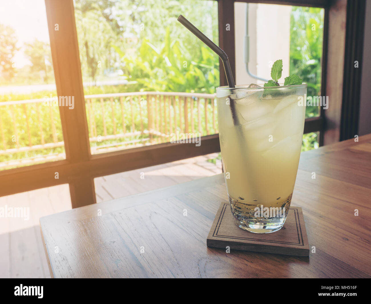 L'eau de citron glacé fruit en verre et bois paille sur table avec copie espace. Banque D'Images