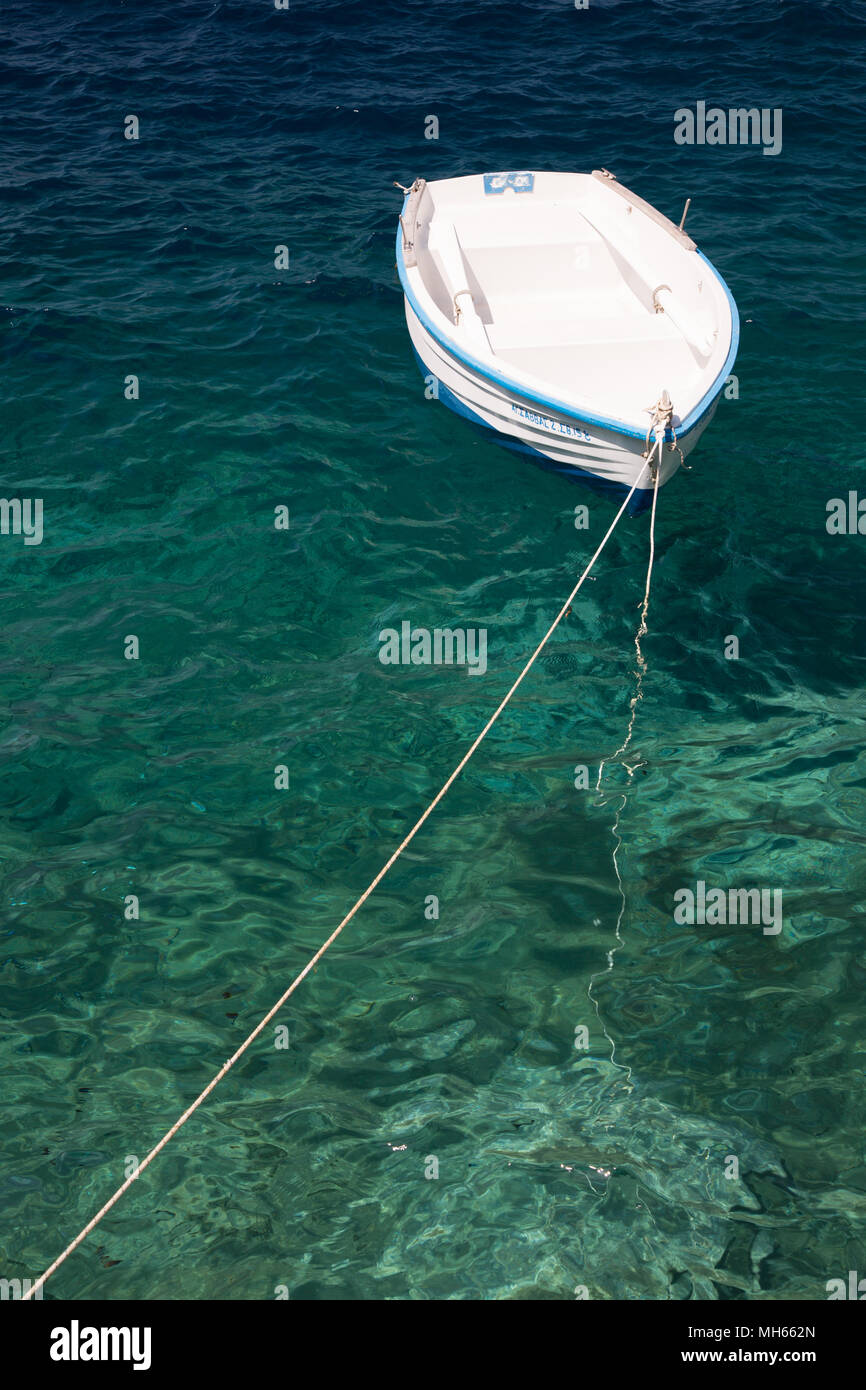 Petit bateau de pêche grec flottant dans l'eau turquoise Banque D'Images