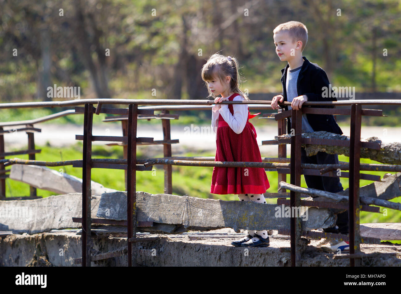 Deux jolies blondes enfants, petite fille aux cheveux long et cute boy leaning on garde-corps en bois de vieux pont à attentivement sur chaude journée ensoleillée. Enfant Banque D'Images