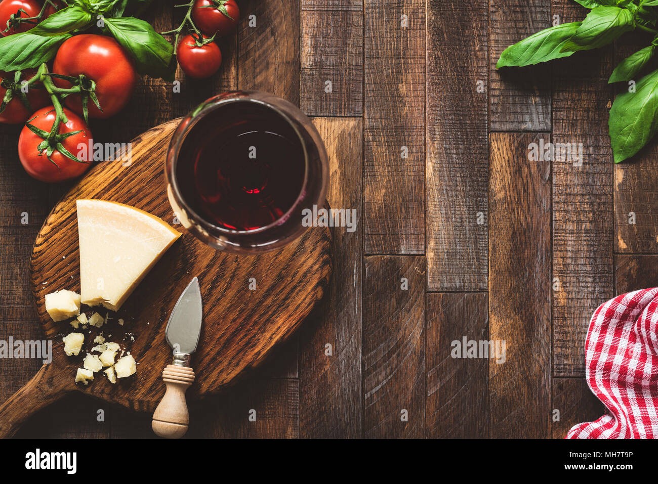 Le fromage parmesan, tomates, basilic et verre de vin rouge. Cuisine italienne. Cuisine italienne rustique sur fond de bois. Le fromage et le vin. Vue d'en haut Banque D'Images