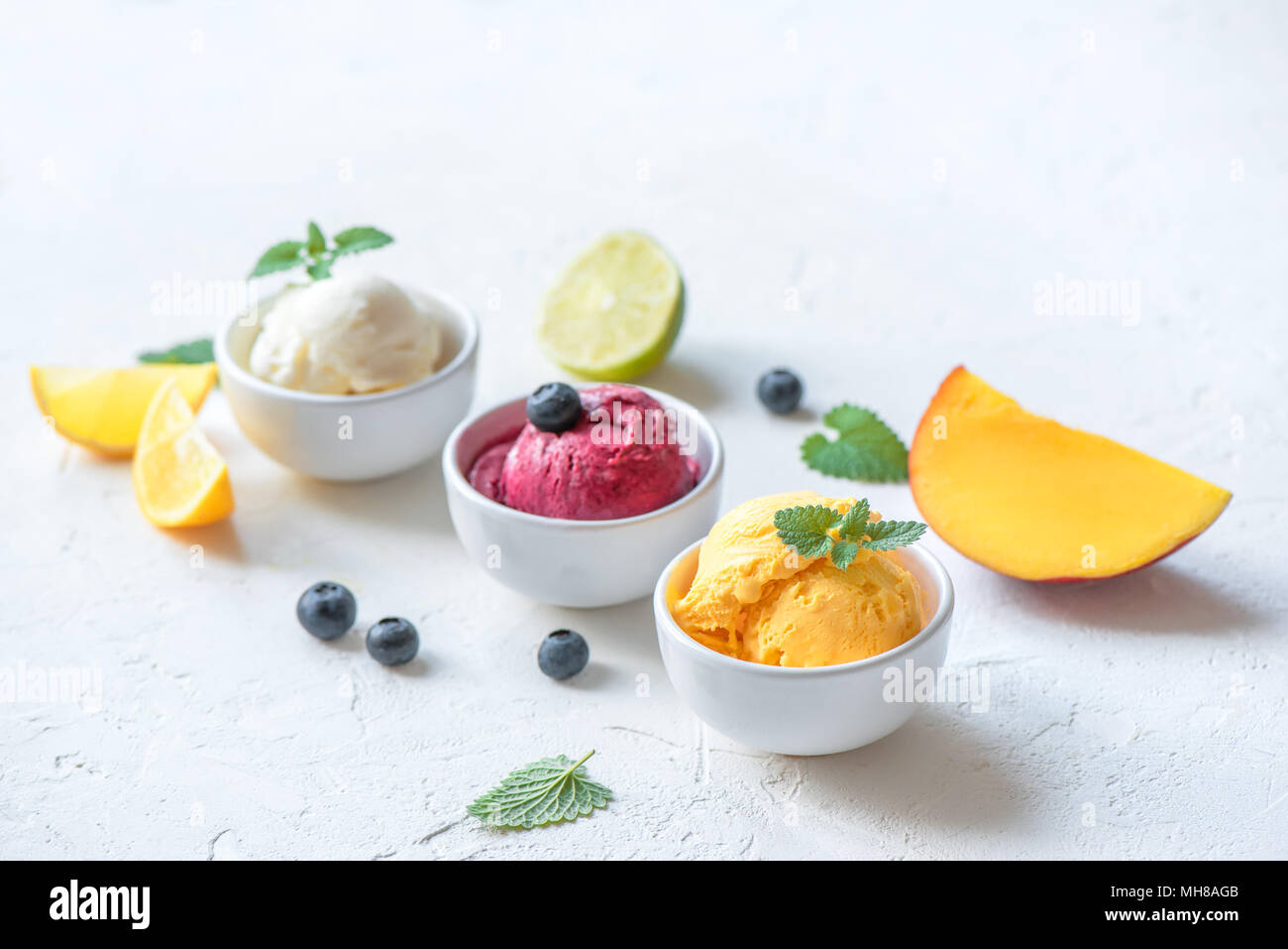 Trois différents fruits et baies des glaces sur fond blanc, copie de l'espace. Le yogourt glacé ou une glace au citron, mangue, les bleuets - l'été en bonne santé Banque D'Images