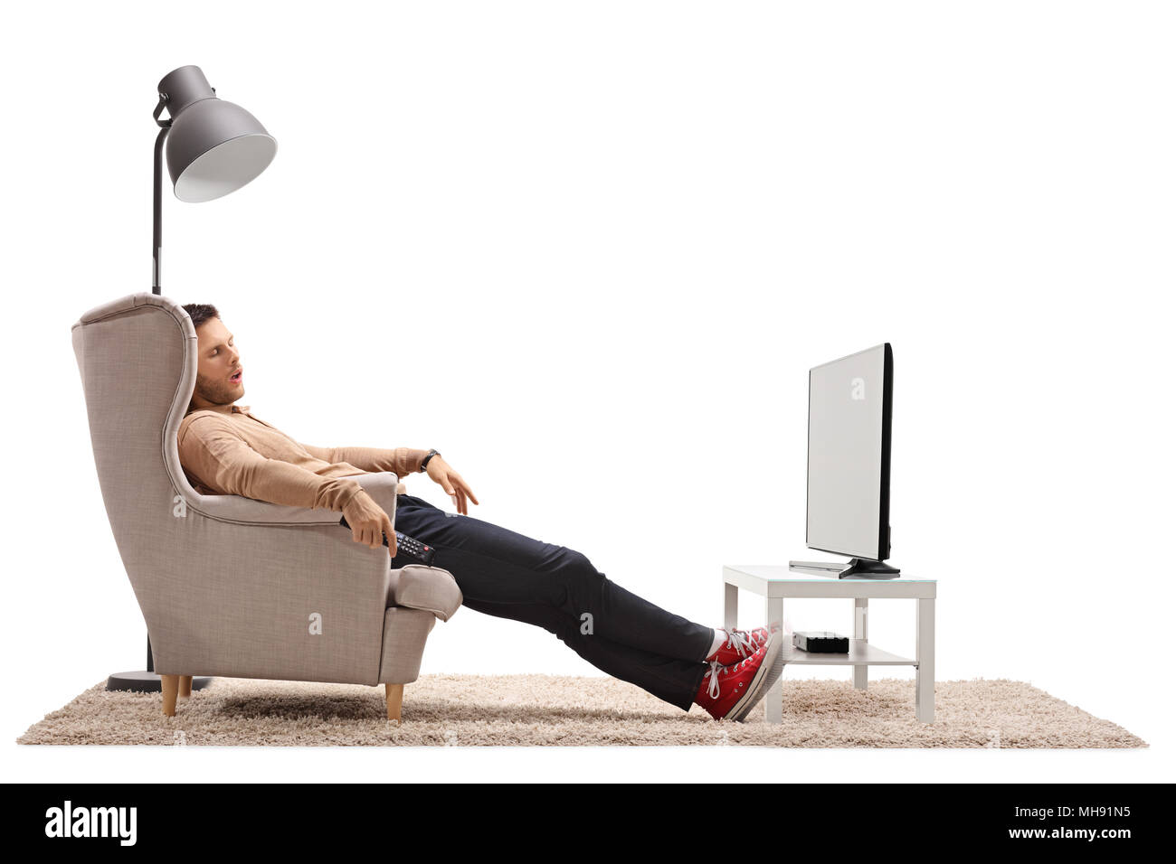 Jeune homme dormant dans un fauteuil devant la télévision isolé sur fond blanc Banque D'Images