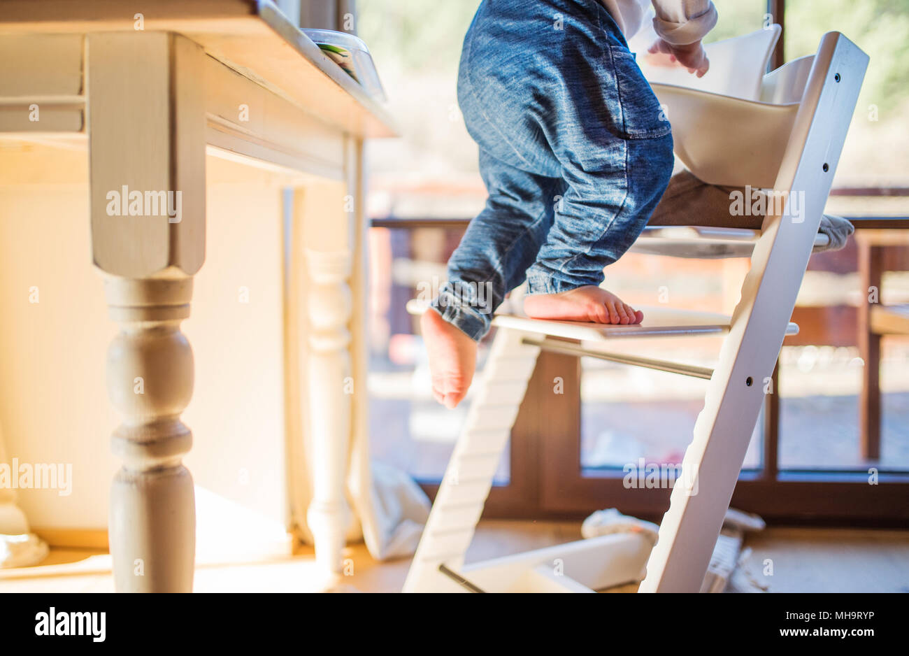 Bébé garçon dans un dangereux à la maison, monter dans une chaise haute  Photo Stock - Alamy