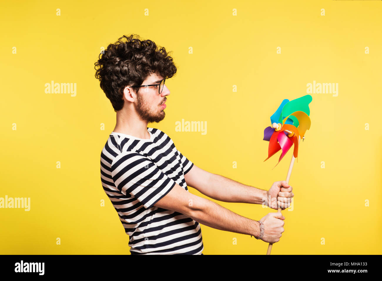 Portrait d'un jeune homme tenant un moulin sur un fond jaune. Banque D'Images