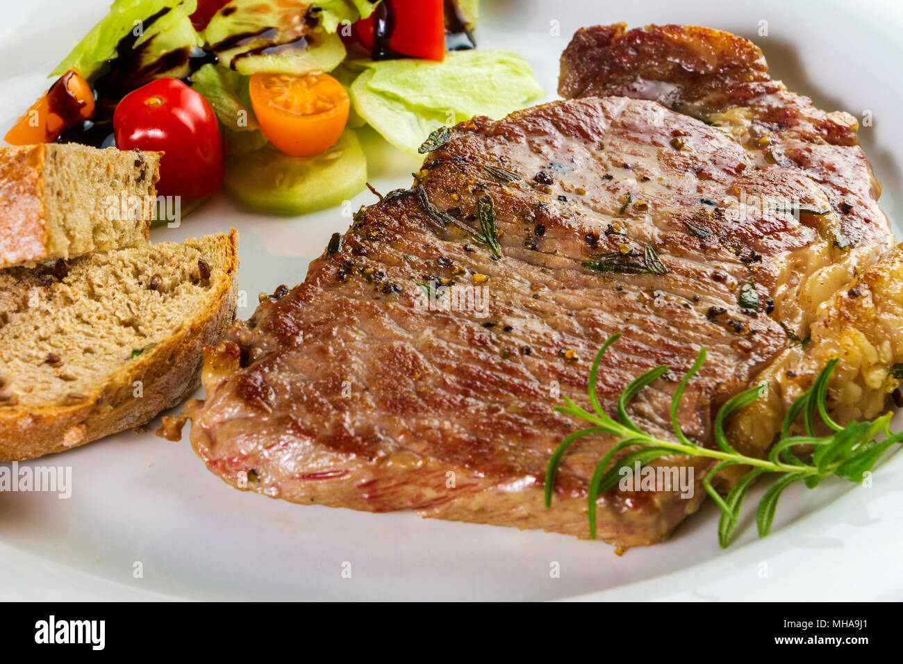 Croupe de boeuf assaisonné mûries ou faux filet steak cuit sur plaque blanche avec de la salade et du pain fait maison Banque D'Images