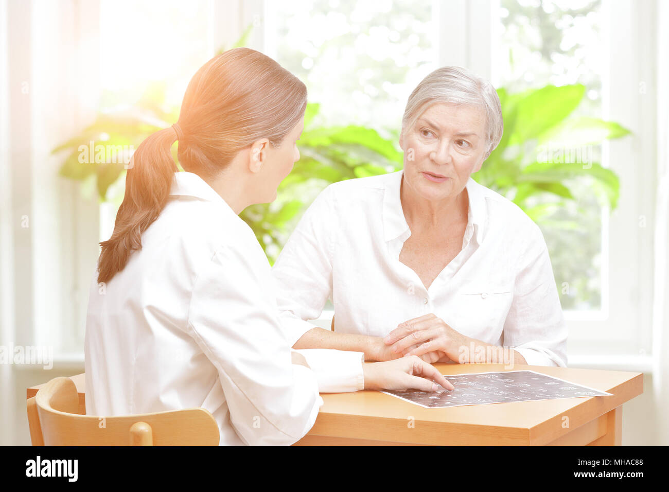 Médecin d'âge moyen de la radiologie dans son bureau en montrant son senior female patient la dernière ct scan de son cerveau Banque D'Images