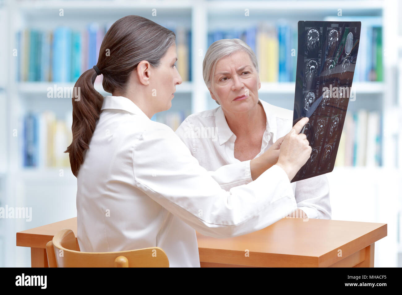 Femme médecin d'âge moyen de discuter avec ses patients avc ct-scan des images de son cerveau Banque D'Images