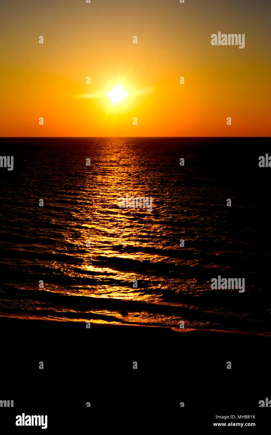 Coucher de soleil avec un faible rayon de soleil dans le carter central long mettez du soleil sur la mer, la mer est à deux tiers inférieurs de la photographie et les soleils Banque D'Images