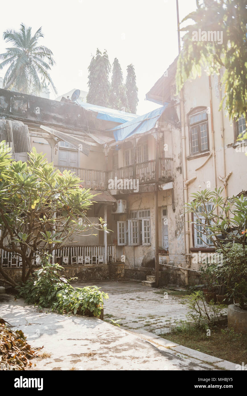 Complexe de bâtiments coloniaux délabrés sur une journée ensoleillée à Mumbai, Inde, entouré d'arbres Banque D'Images