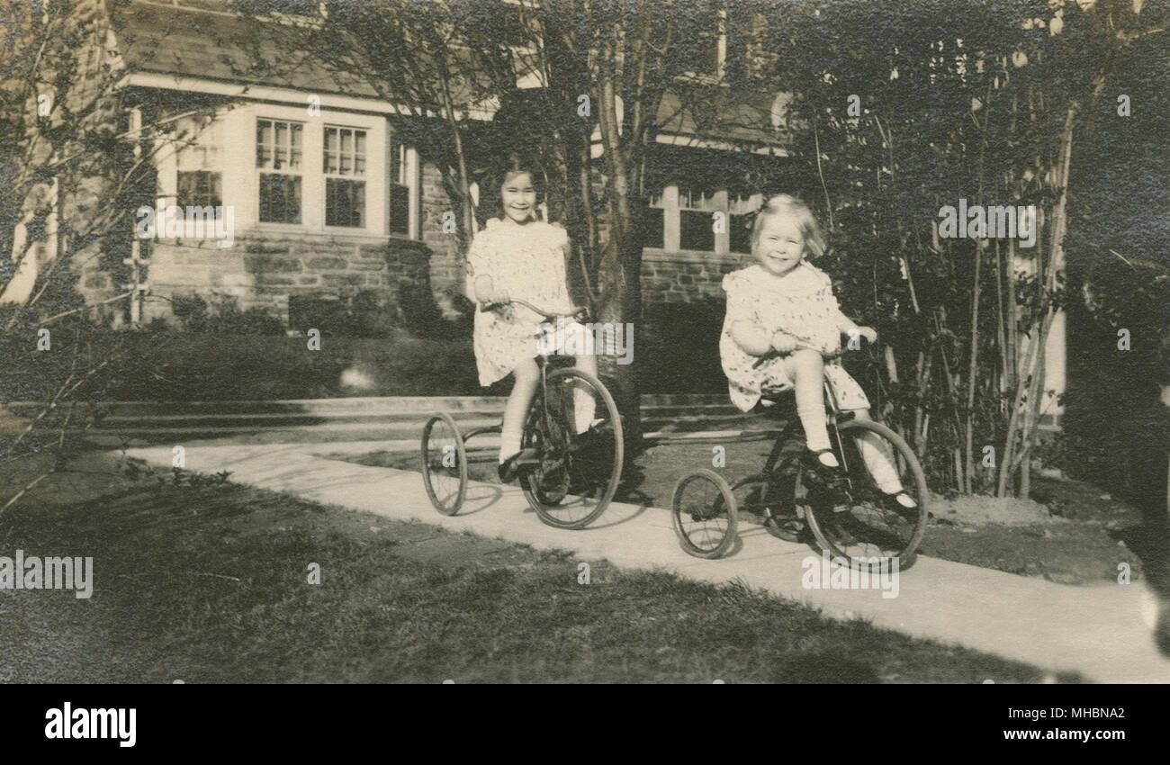 Meubles anciens c1923 photo, deux filles circonscription tricycles à la maison. Lieu inconnu, peut-être New York ou le New Jersey, USA. SOURCE : GÉLATINE D'ORIGINE. Banque D'Images