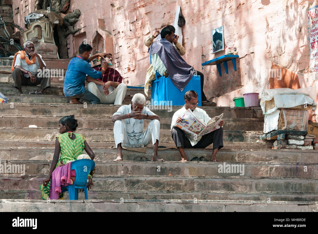 Varanasi, Inde - le 12 mars 2017 : les Indiens assis sur l'escalier et de lecture à la ville sainte de Varanasi en Inde. Banque D'Images