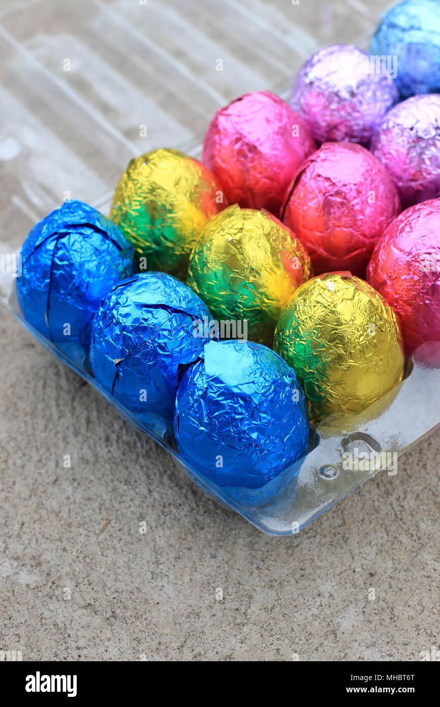 Main tenant les Œufs en chocolat coloré sur carton plastique Banque D'Images