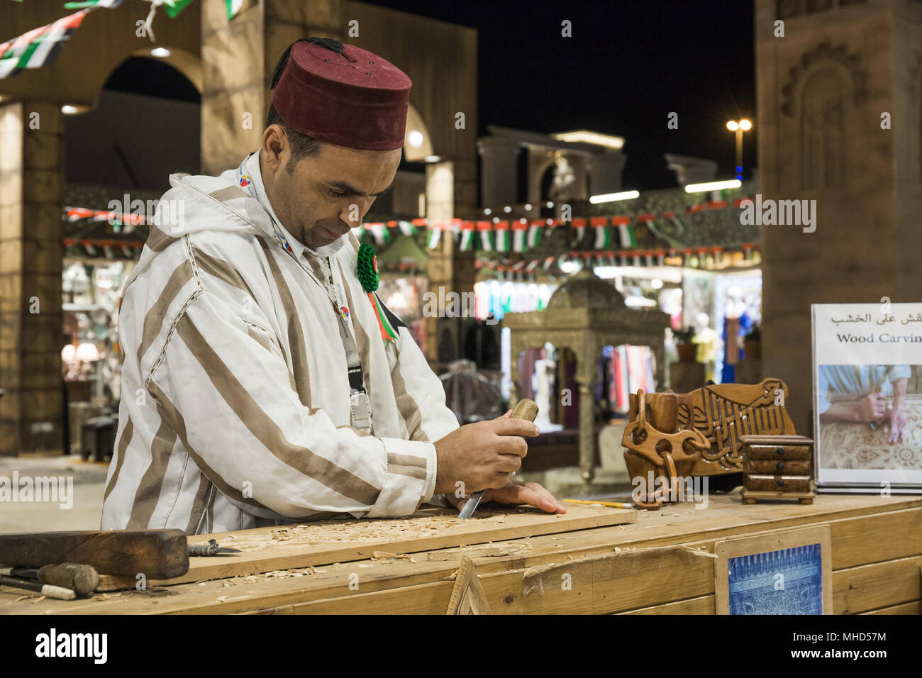 Dubaï, Émirats arabes unis - 4 décembre 2017 : artisan Sculpteur sur bois dans les vêtements nationaux dans le pavillon de la Turquie en Village mondial Banque D'Images
