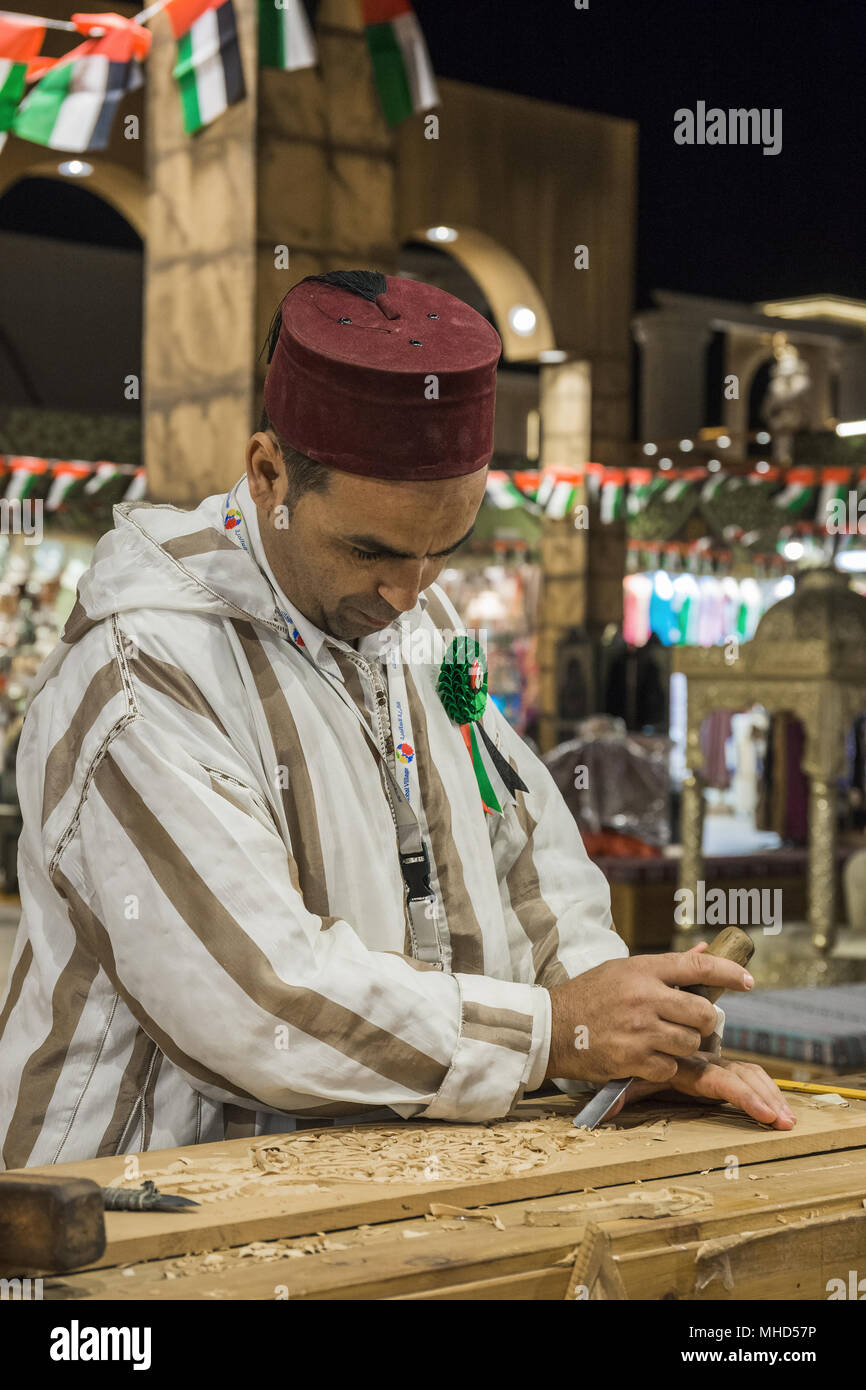 Dubaï, Émirats arabes unis - 4 décembre 2017 : artisan Sculpteur sur bois dans les vêtements nationaux dans le pavillon de la Turquie en Village mondial Banque D'Images
