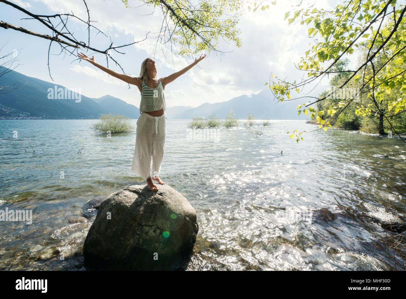 Jeune femme debout sur un rocher au-dessus du lac bras tendus pour la liberté et les émotions positives. Les gens voyagent sans souci du bien-être concept. La Suisse Banque D'Images