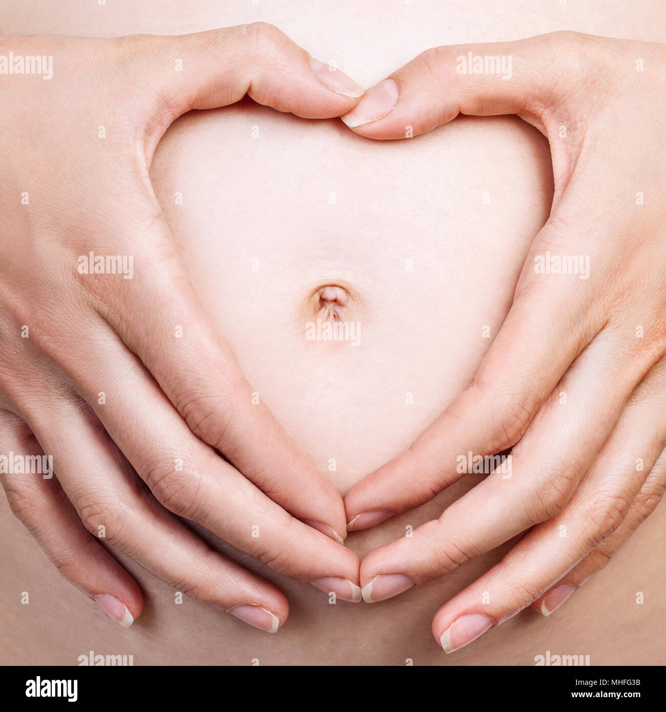 Pregnant woman holding ses mains en forme de coeur sur le ventre. Banque D'Images