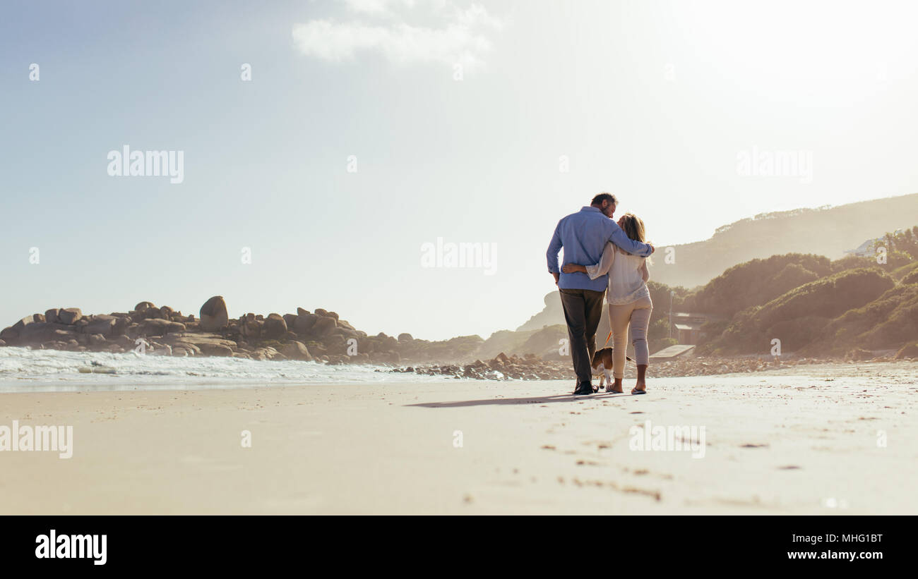 Couple romantique balade le long de la plage avec un chien. Senior couple strolling sur mer avec chien. Banque D'Images