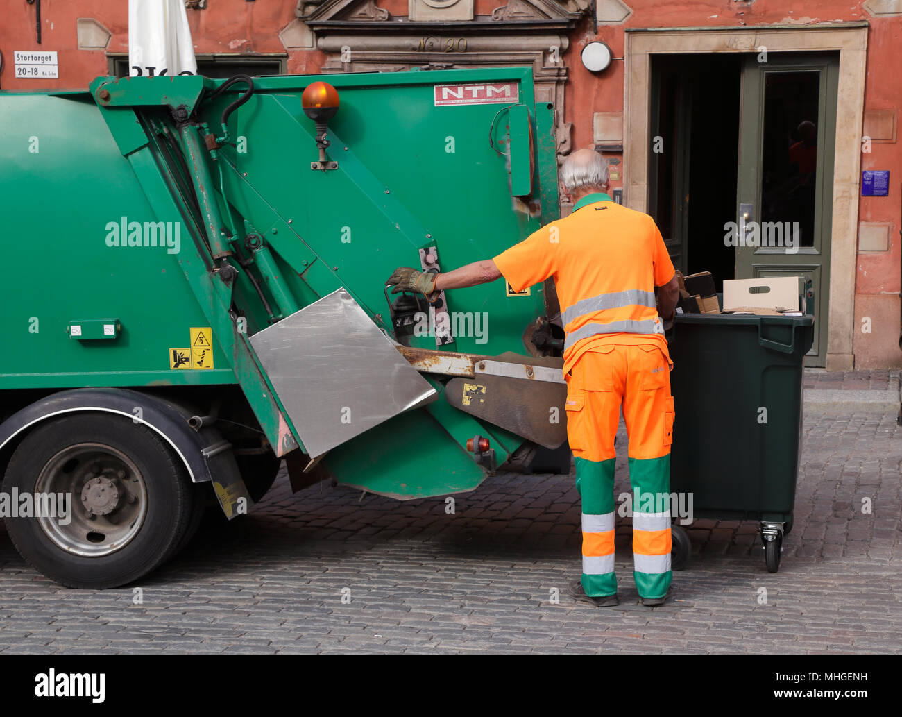 Stockholm, Suède - le 18 juin 2013 : un homme en salopette orange se vide ordures dans un camion poubelle verte sur la place principale de la Vieille Ville Banque D'Images