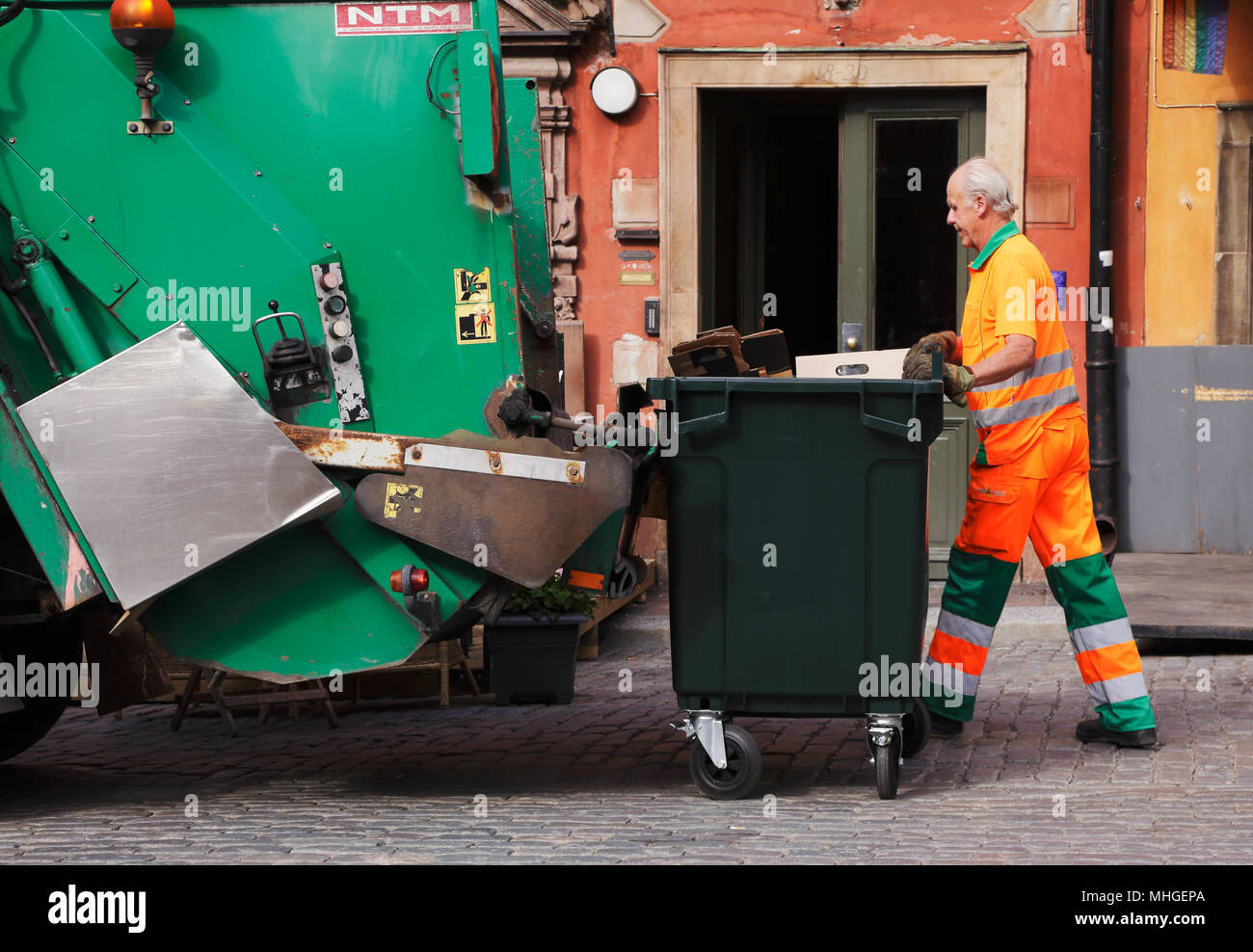 Stockholm, Suède - le 18 juin 2013 : un homme en salopette orange se vide ordures dans un camion poubelle verte sur la place principale de la Vieille Ville Banque D'Images