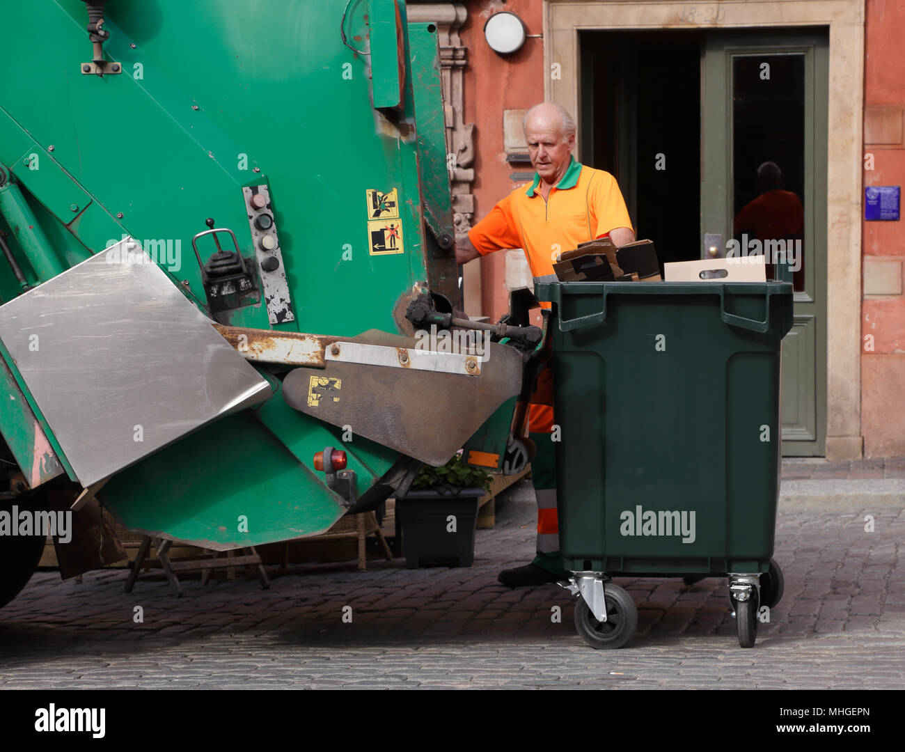 Stockholm, Suède - le 18 juin 2013 : un homme en salopette orange se vide ordures dans un camion poubelle verte sur la place principale de la Vieille Ville Banque D'Images