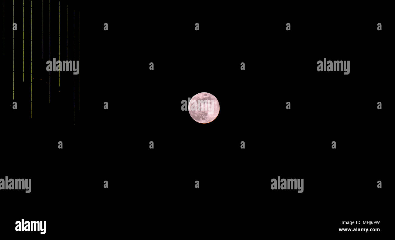 Pleine lune en avril s'appelle Lune Rose, mais pour des raisons inconnues de la photographe, ce lever de lune n'apparaissent rose avec haut-ri moderne éclairé Banque D'Images