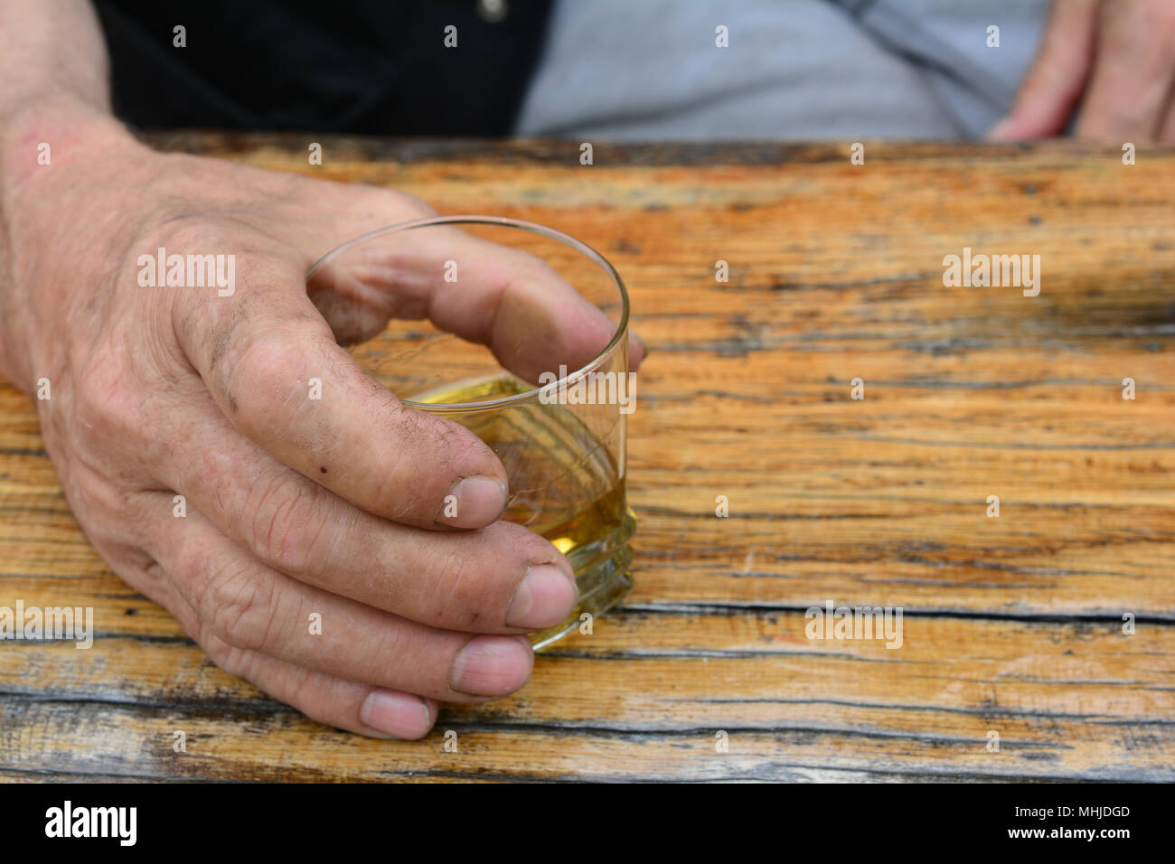 Man's hand holding glass avec de vieux, de la bonne eau-de-vie de prune sur la vieille table en chêne, grunge Banque D'Images