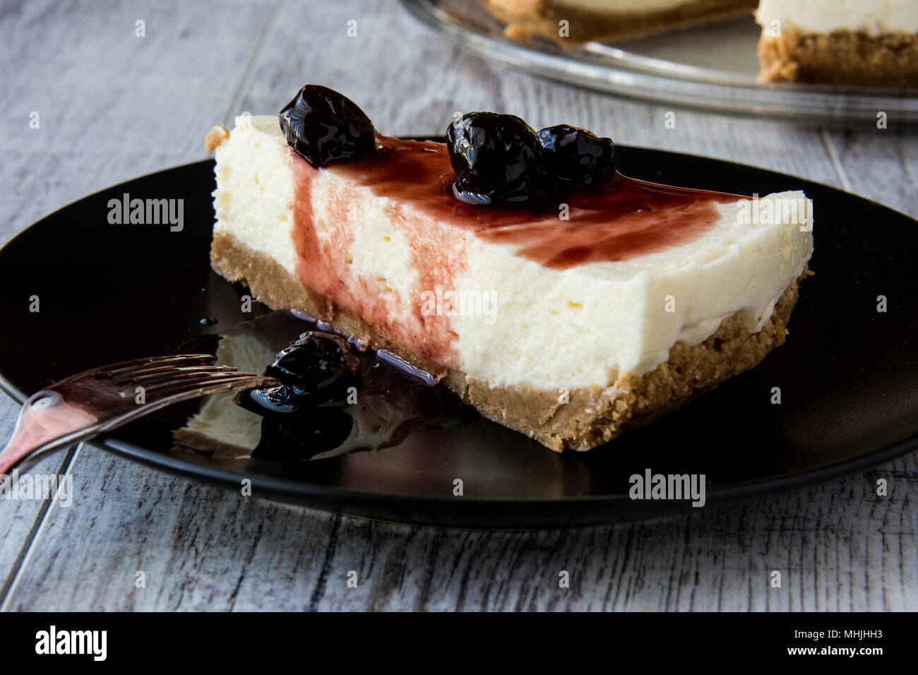 Cherry Cheesecake maison avec la fourchette dans la plaque noire. Banque D'Images