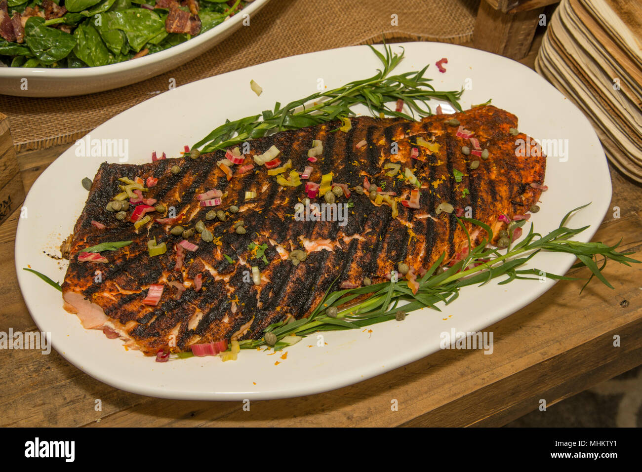 Un filet de saumon est présenté sur un plateau après avoir été noirci et assaisonné sur un grill. Banque D'Images