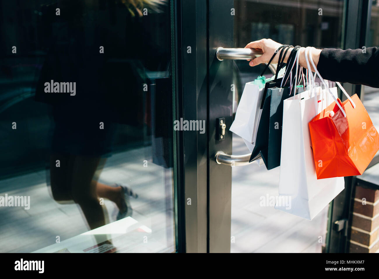 La main féminine holding shopping bags et porte ouverte de shop Banque D'Images