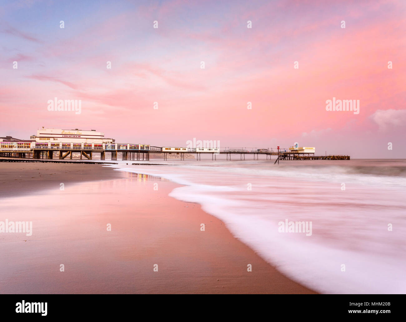 Lever de soleil sur Rose Jetée de Sandown avec la mer roulant sur la plage Banque D'Images