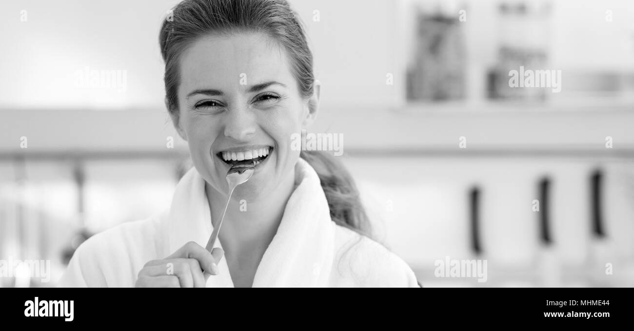 Smiling young woman in bathrobe eating healthy breakfast Banque D'Images