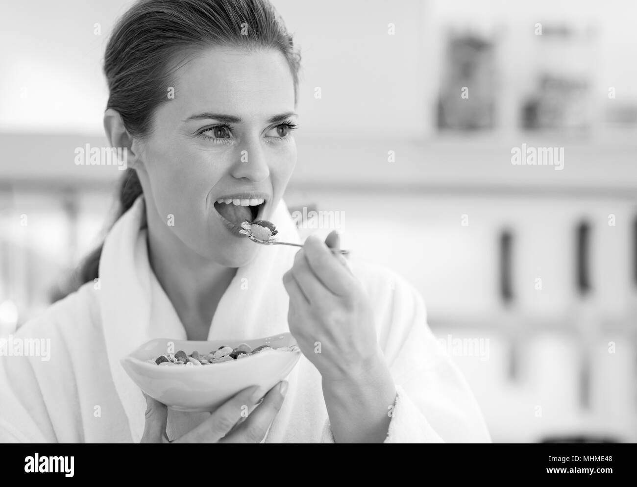 Jeune femme au foyer en peignoir avoir petit-déjeuner sain dans la cuisine Banque D'Images