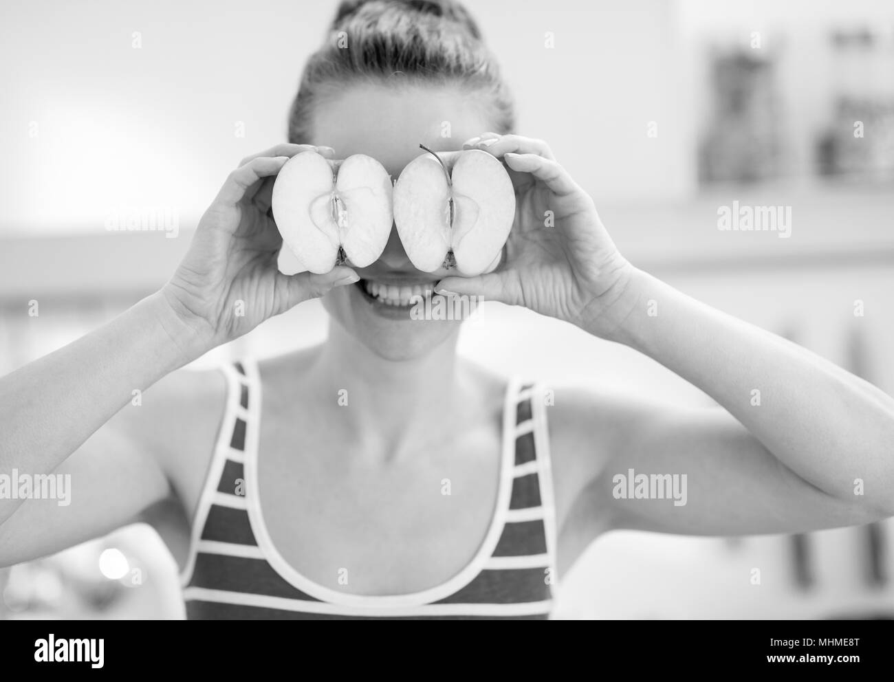Happy young woman holding deux tranches de pomme en face des yeux Banque D'Images