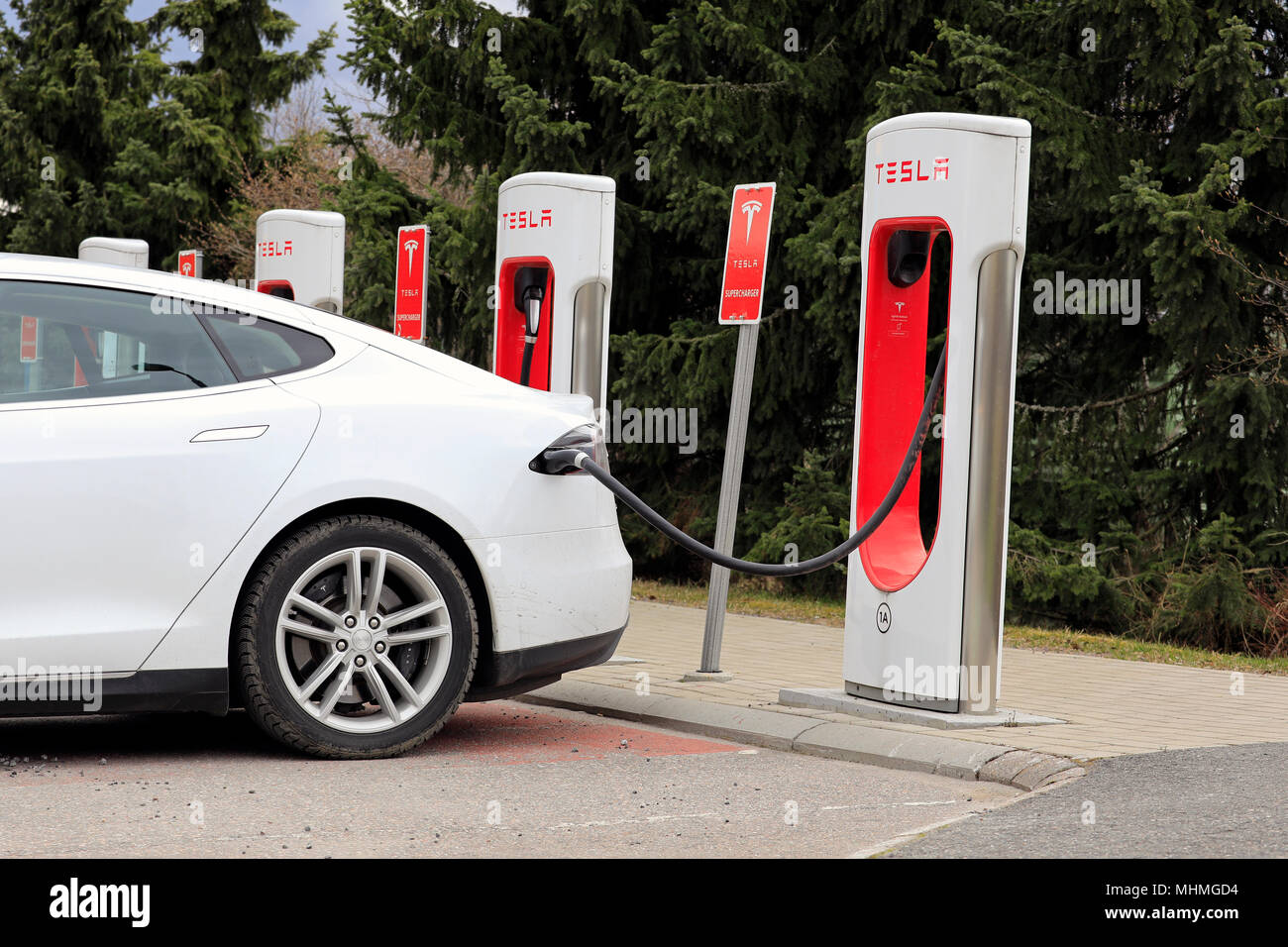 Vue de côté détail de Tesla Model S blanc voiture électrique connecté à la station de charge et a un jour de printemps en Finlande, Paimio - 28 Avril Banque D'Images