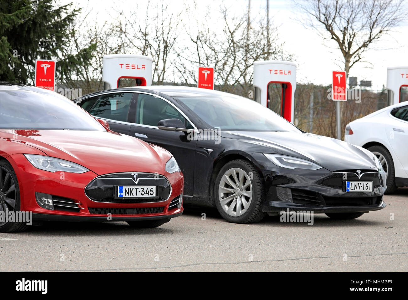 Deux voitures électriques Tesla Model S, rouge de la conception précédente, noir de conception mise à jour, sont à la charge de la batterie station de compresseur sur un jour de printemps Banque D'Images
