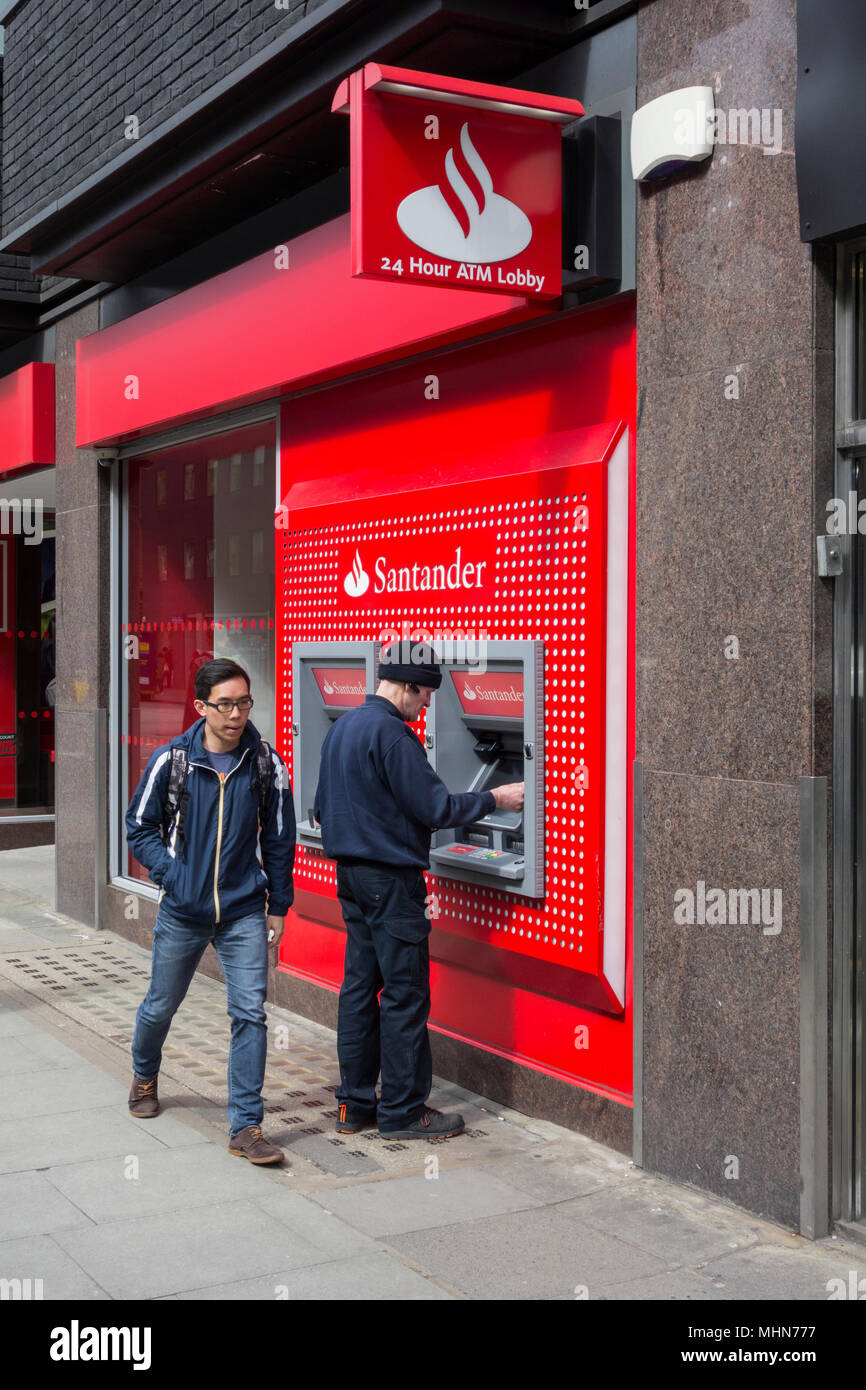 Un homme un retrait d'argent à partir de la direction de Santander sur Tottenham Court Road, Bloomsbury, London, W1, Banque D'Images