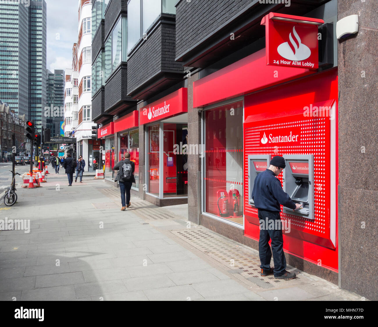 Un homme un retrait d'argent à partir de la direction de Santander sur Tottenham Court Road, Bloomsbury, London, W1, Banque D'Images