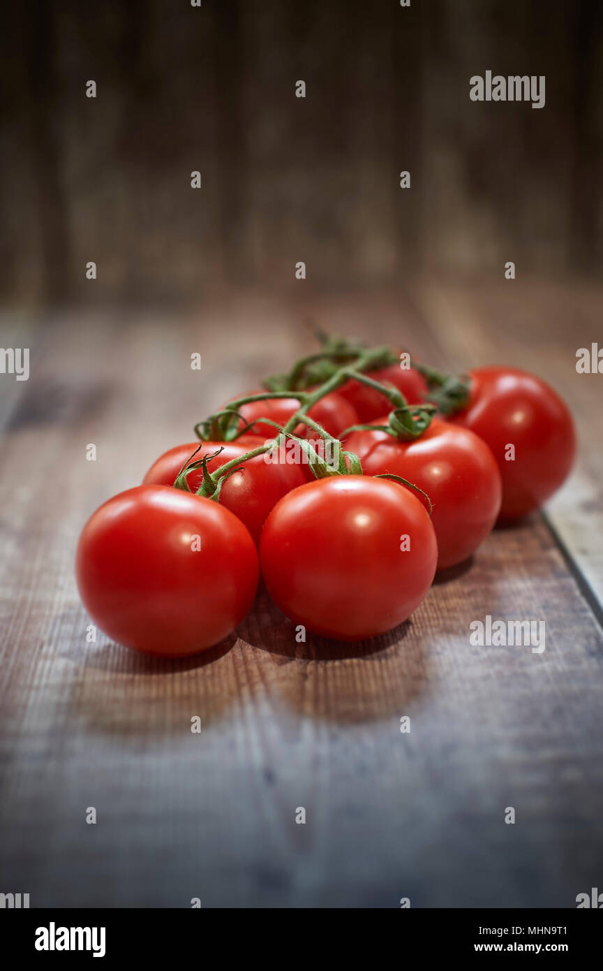 Des tomates mûries sur vigne de table en bois Banque D'Images