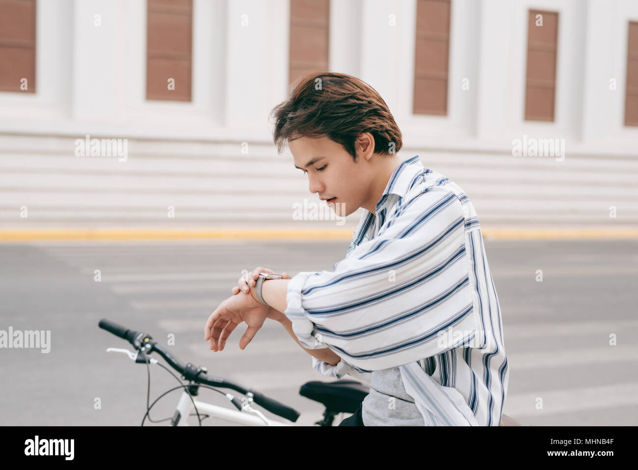 Jeune beau mec avec un vélo dans la rue, à la recherche à regarder. Banque D'Images