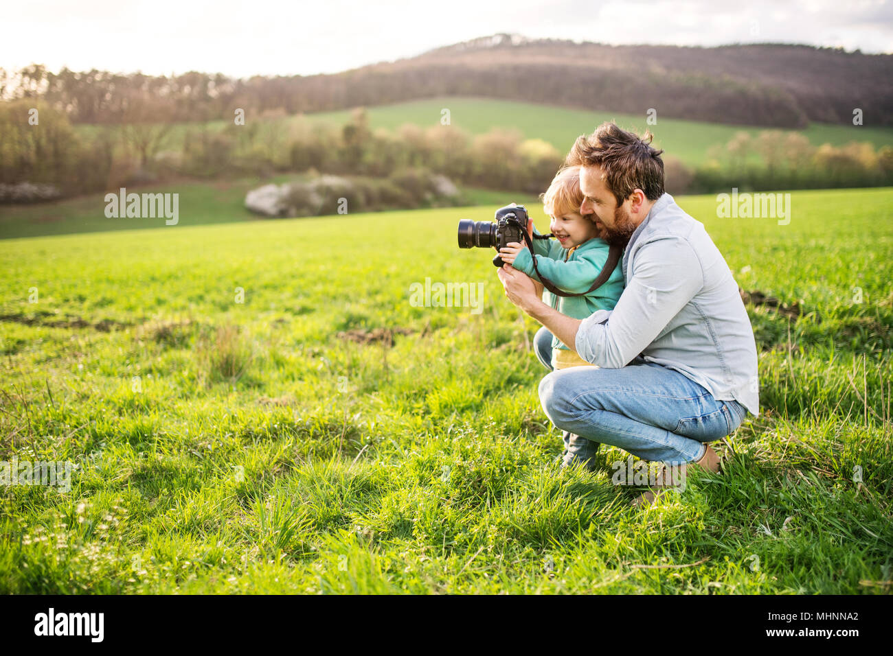 Un père et son petit garçon avec un appareil photo à l'extérieur au printemps la nature. Banque D'Images