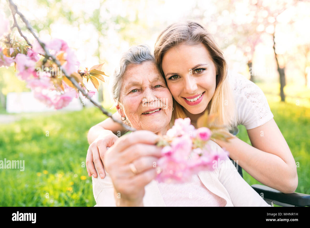 Grand-mère âgée en fauteuil roulant avec sa petite-fille au printemps la nature. Banque D'Images
