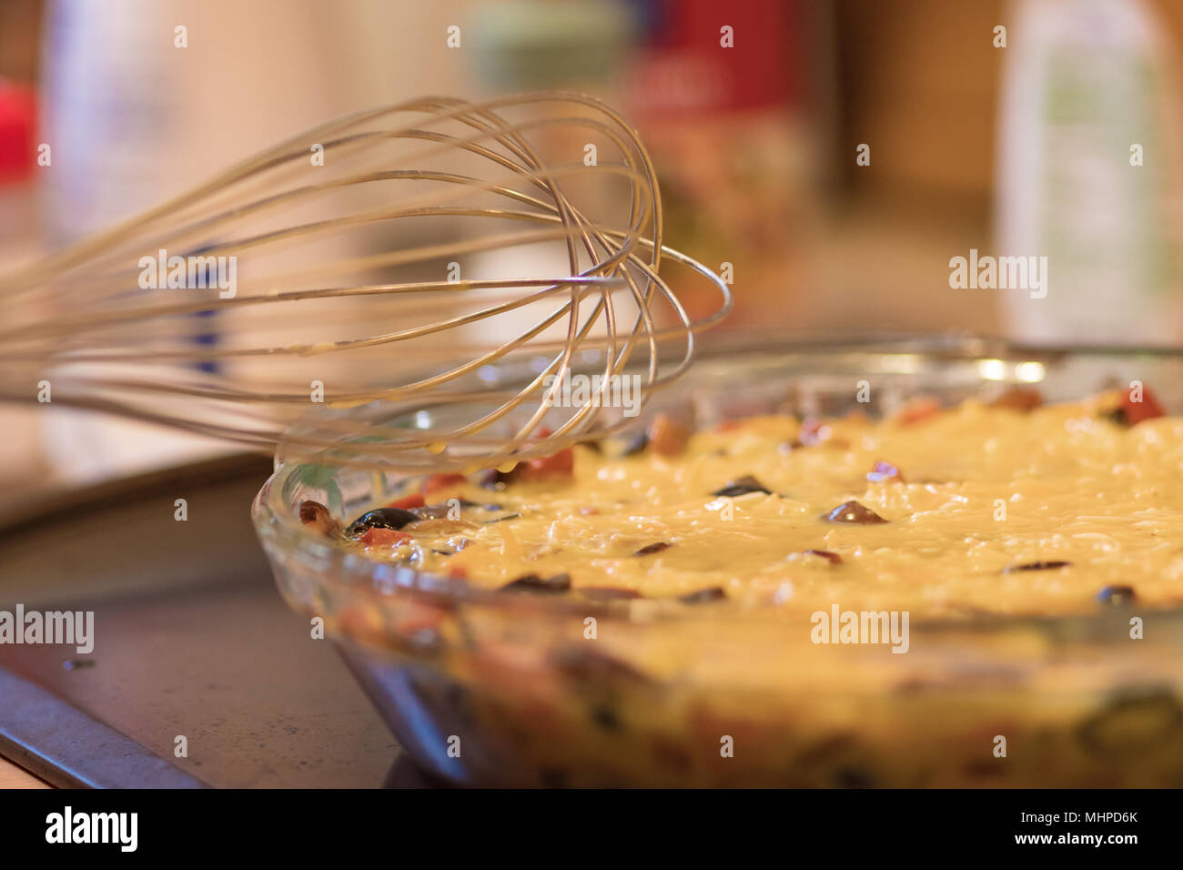 Le fromage, œuf et mélange de légumes dans un plat de cuisson en verre avec wisk. Banque D'Images