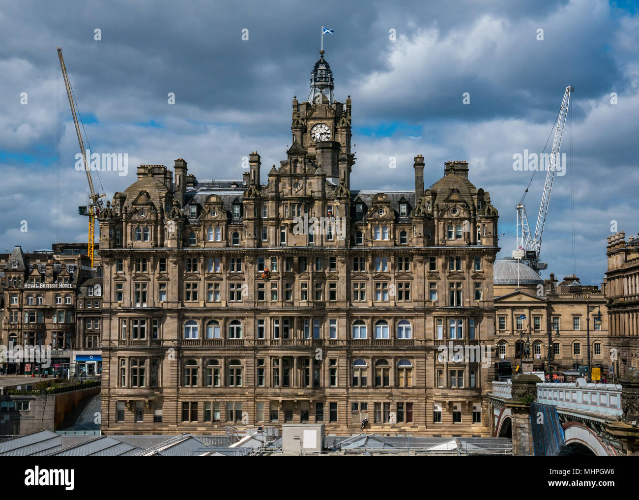 Rocco Forte Balmoral Hotel, Princes Street, Edinburgh, Royaume-Uni, avec ciel bleu et de la construction de grues. Ouvriers en orange la descente en rappel pour nettoyer windows Banque D'Images