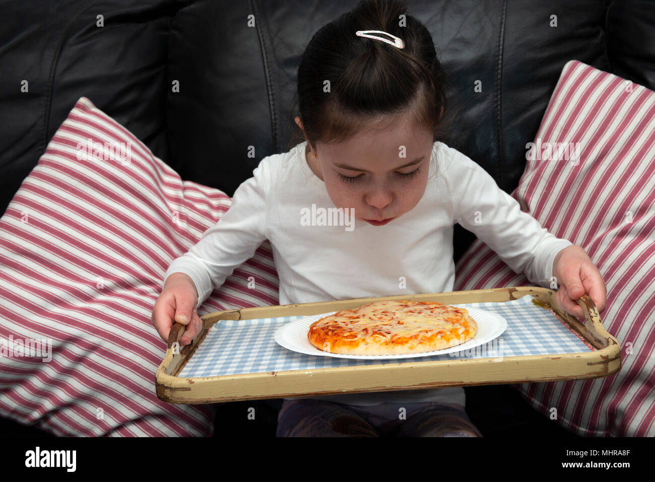 Jeune fille en soufflant sur une pizza chaude Banque D'Images