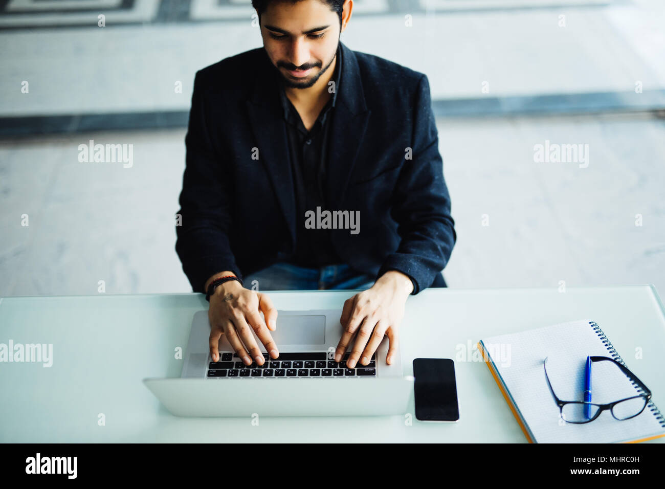 Vue directement au-dessus de l'indian man typing on laptop in office Banque D'Images