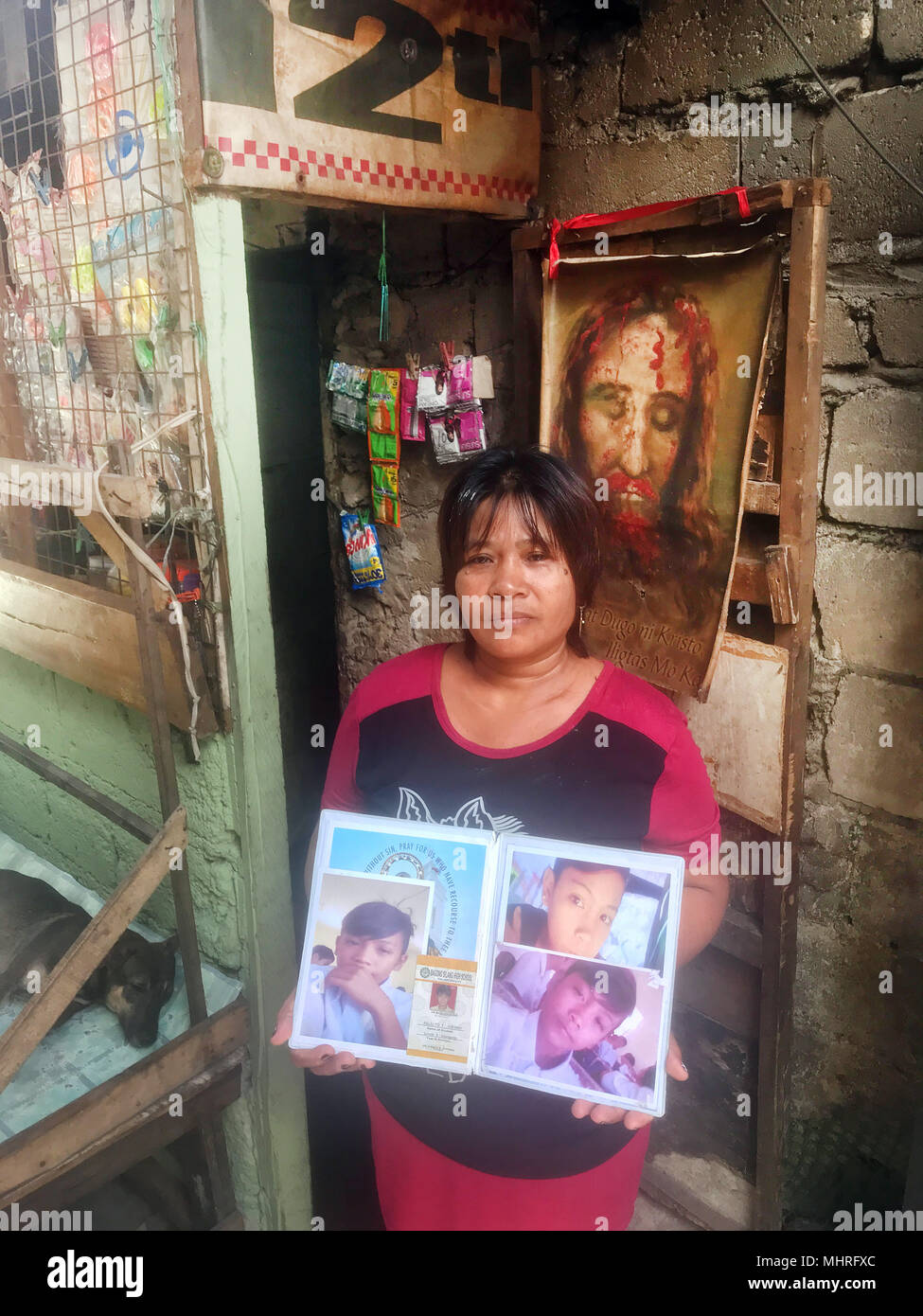 Déposée - 19 avril 2018, Philippines, Manille : Les Philippins Emily Soriano montrant des photos en face de sa maison à Bagong Silang de son fils qui a été tué. Le jeune homme de 15 ans est l'une des milliers de victimes de la guerre anti-drogue menées par le président Rodrigo Duterte. Photo : Christoph Sator/dpa Banque D'Images