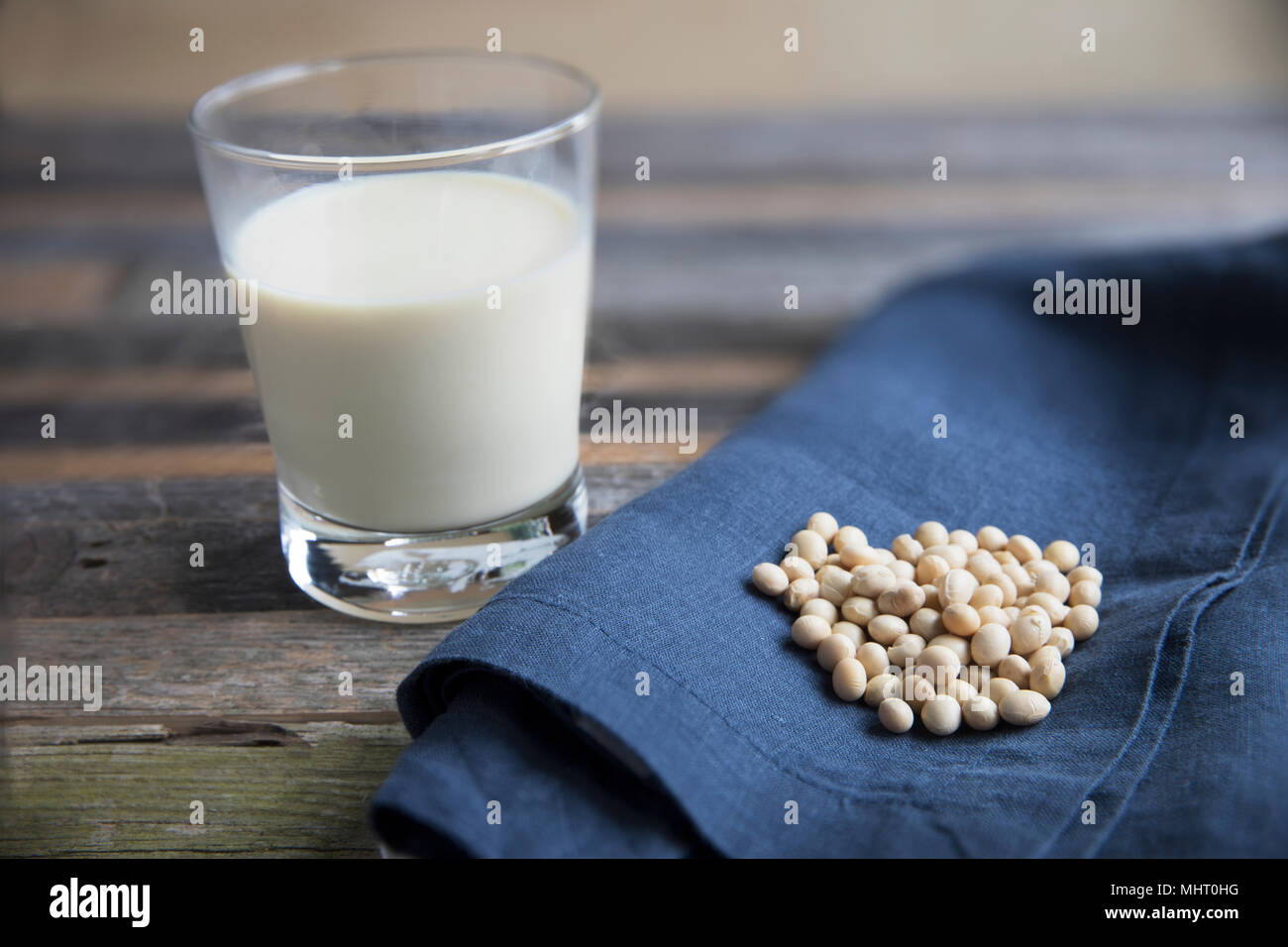 Soja sur serviette bleu avec verre de lait de soja sur la vieille table en bois. Banque D'Images