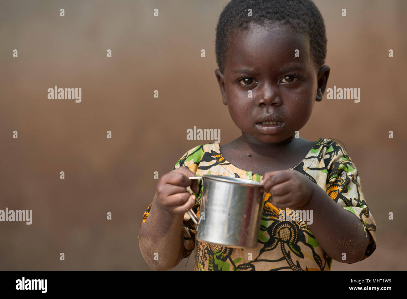 Trois ans Janesi Manuel, personnes déplacées par les conflits armés, est titulaire d'une tasse de bouillie dans un camp de personnes déplacées au Soudan du Sud. Banque D'Images