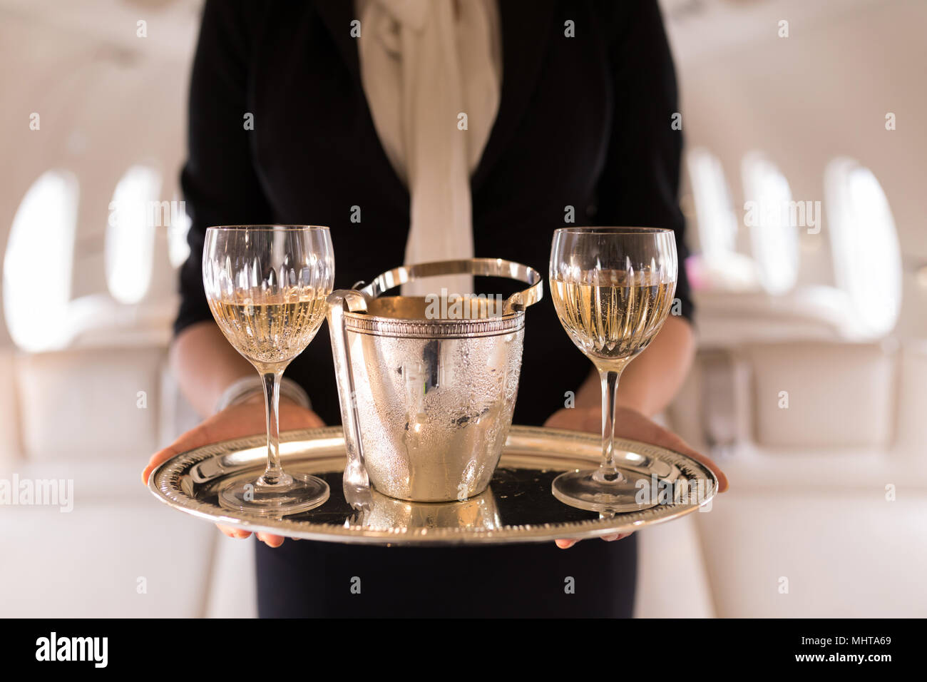 Agent de bord servant verres de champagne en jet privé Banque D'Images
